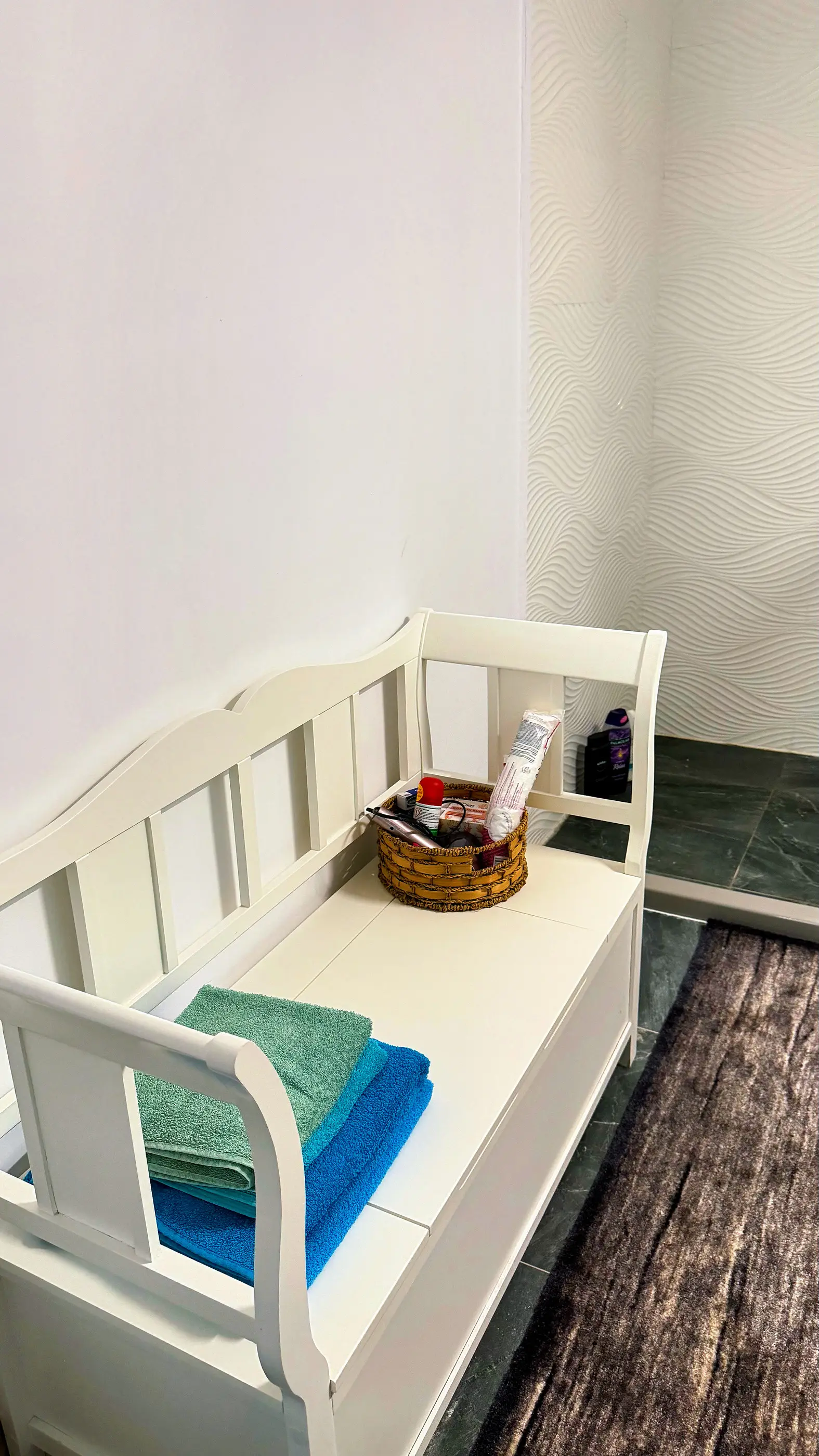 A white bench with fresh towels in the bathroom
