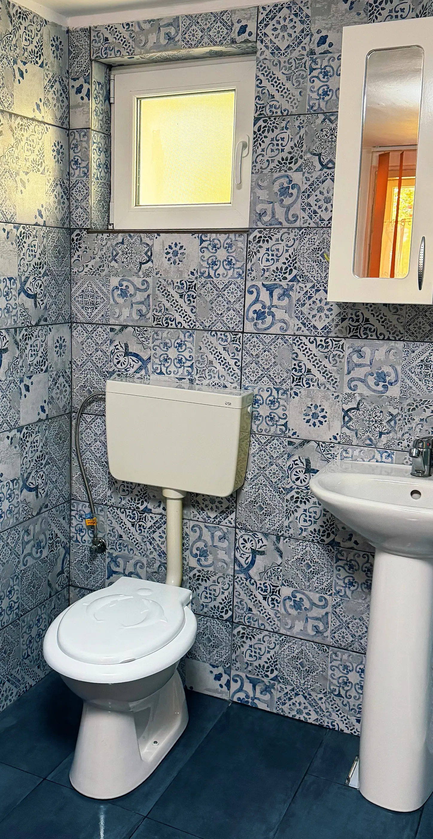 The bathroom with blue patterned tiles and a window