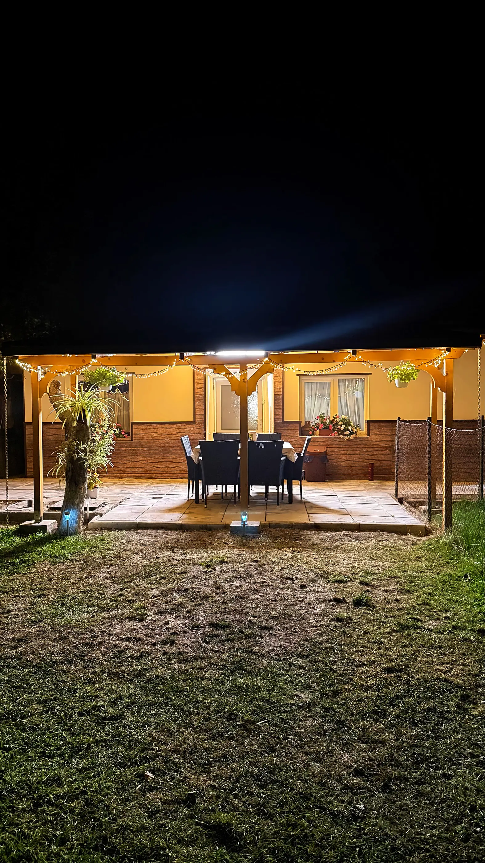 The pergola terrace lit at night, with the table set