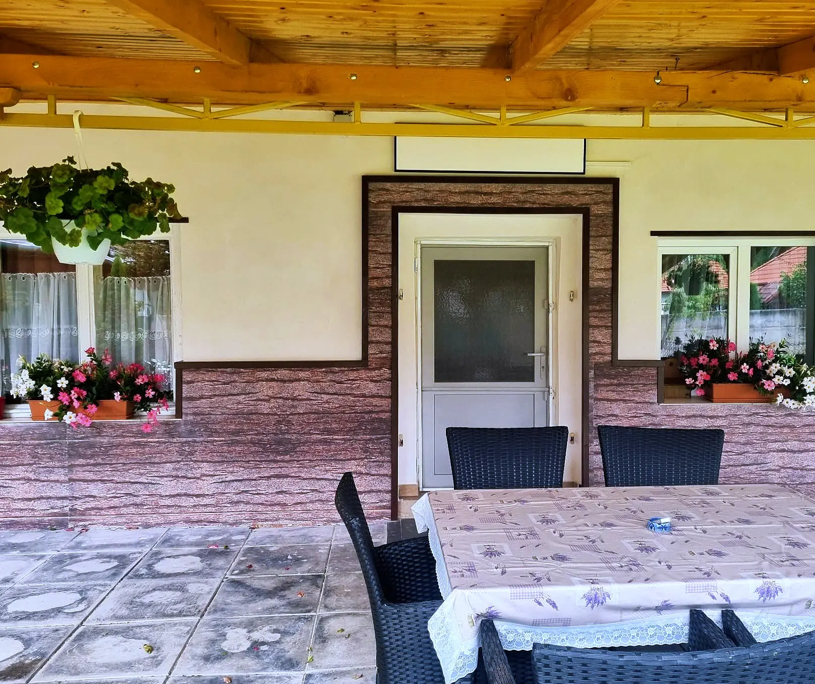The terrace entrance, with flowers at the windows and the outdoor table
